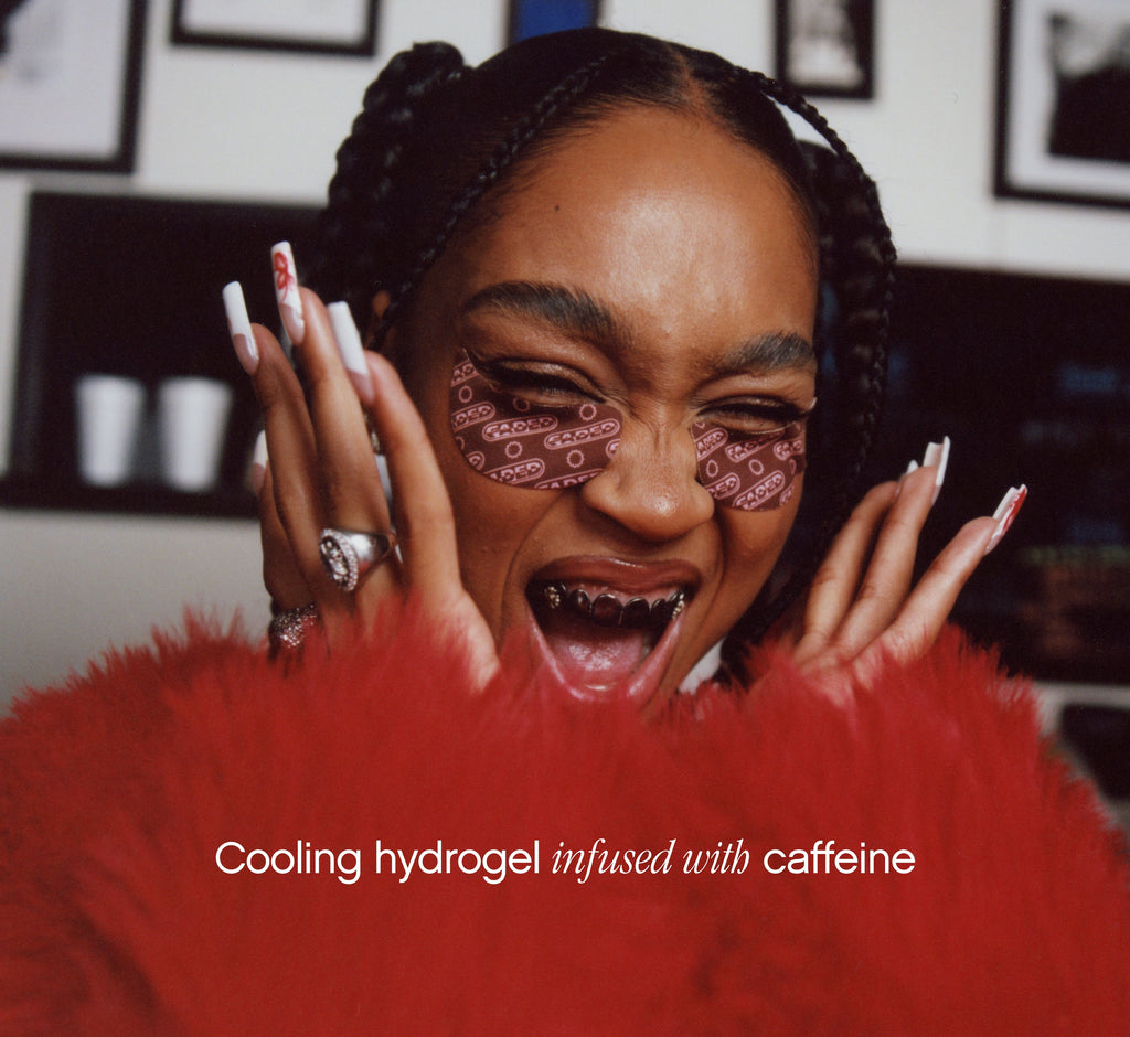 Brightening under eye patches from Topicals Faded worn by a smiling woman with box braids, highlighting the cooling caffeine-infused hydrogel formula.